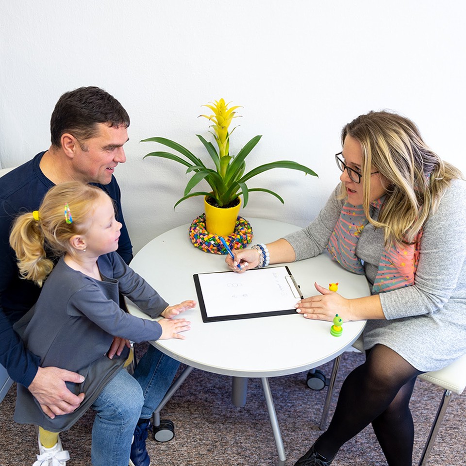 A social worker meets with a father and his young daughter.