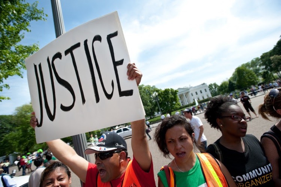 A protestor in a group holds up a sign reading “justice.”