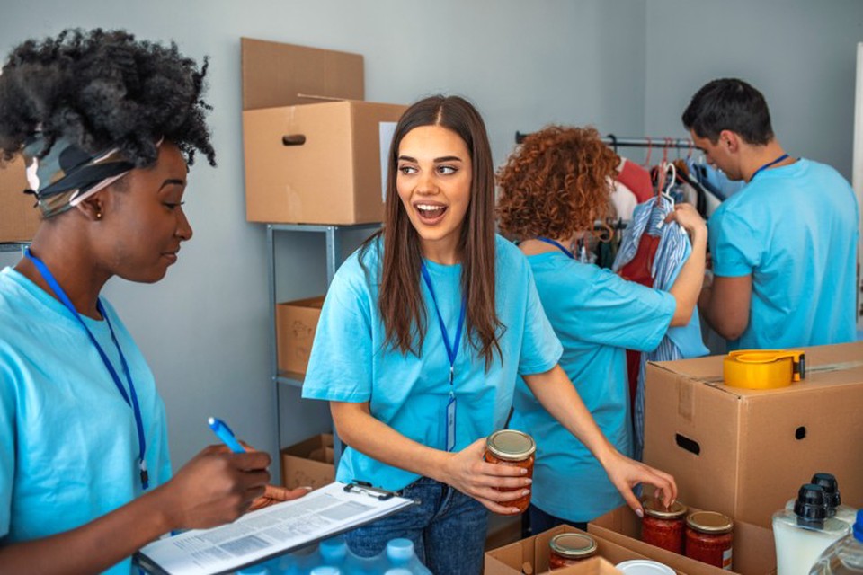 Four people wearing matching blue T-shirts sort donations of food and clothing.