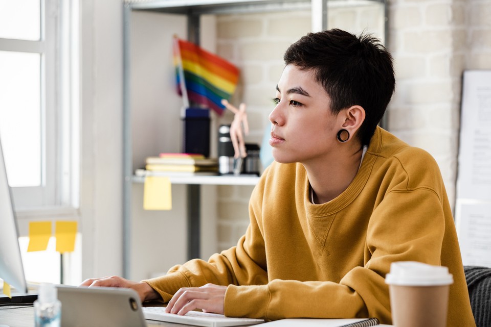 An online student works on their computer while seated at a desk.