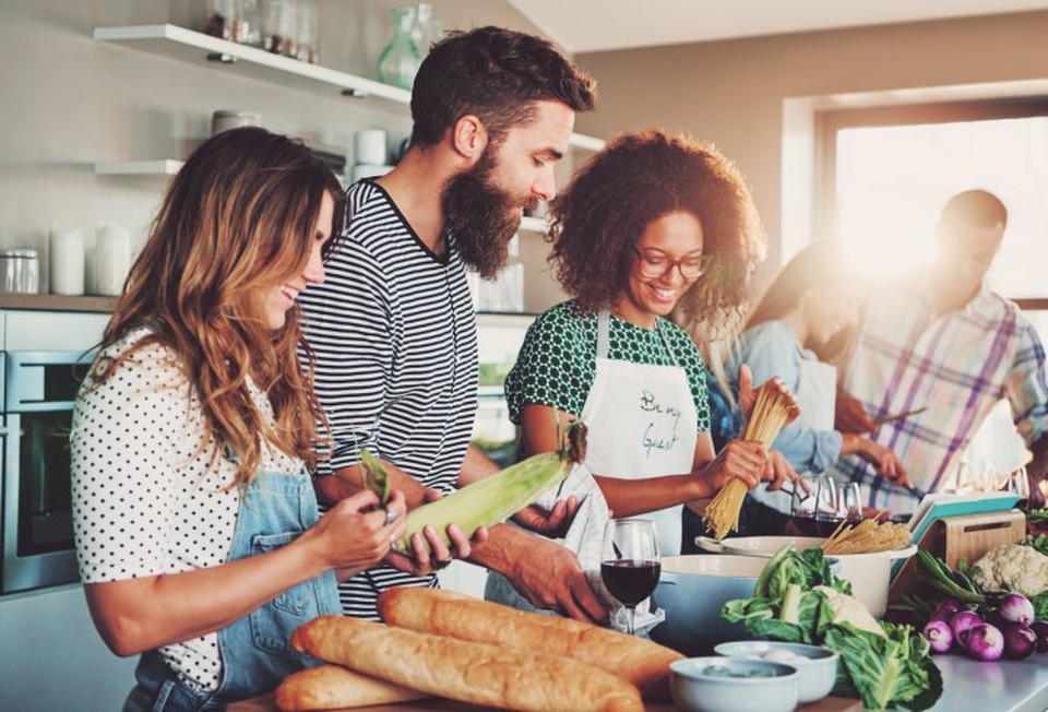A group of community-based health educators stand at a kitchen counter preparing a healthy meal.