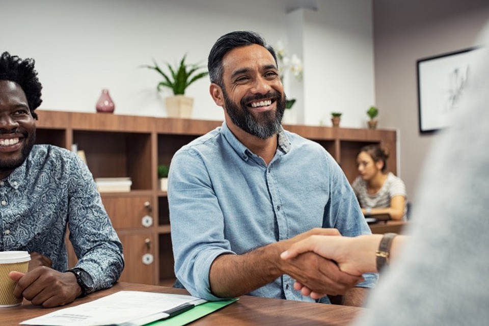 A smiling social worker shakes a client’s hand