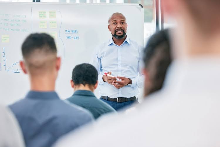 A social worker in front of a white board conducts a job training session.