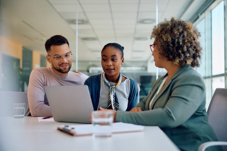 A social worker meets with a pair of clients in an office.